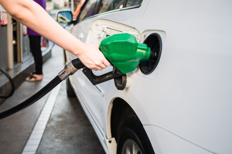 Female hand holding green pump filling gasoline