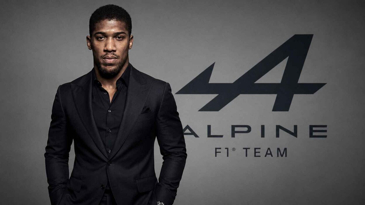 Boxer in a black suit standing in front of the Alpine F1 Team logo.