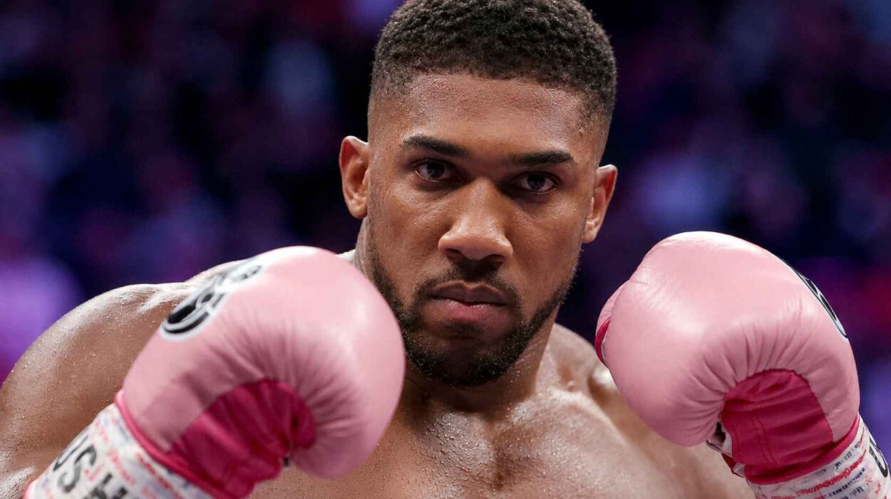 Anthony Joshua wearing pink boxing gloves in a fighting stance.