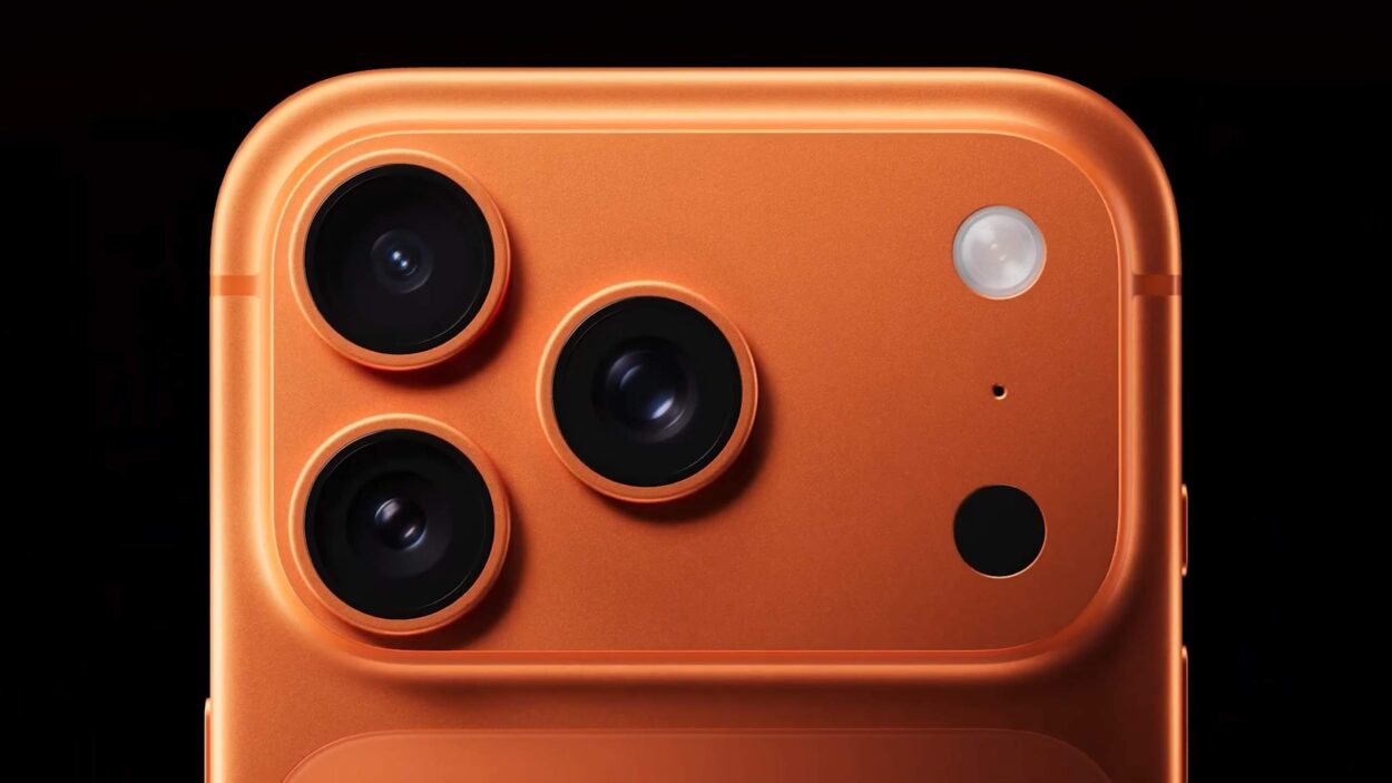 Close-up of an orange smartphone with three rear camera lenses.