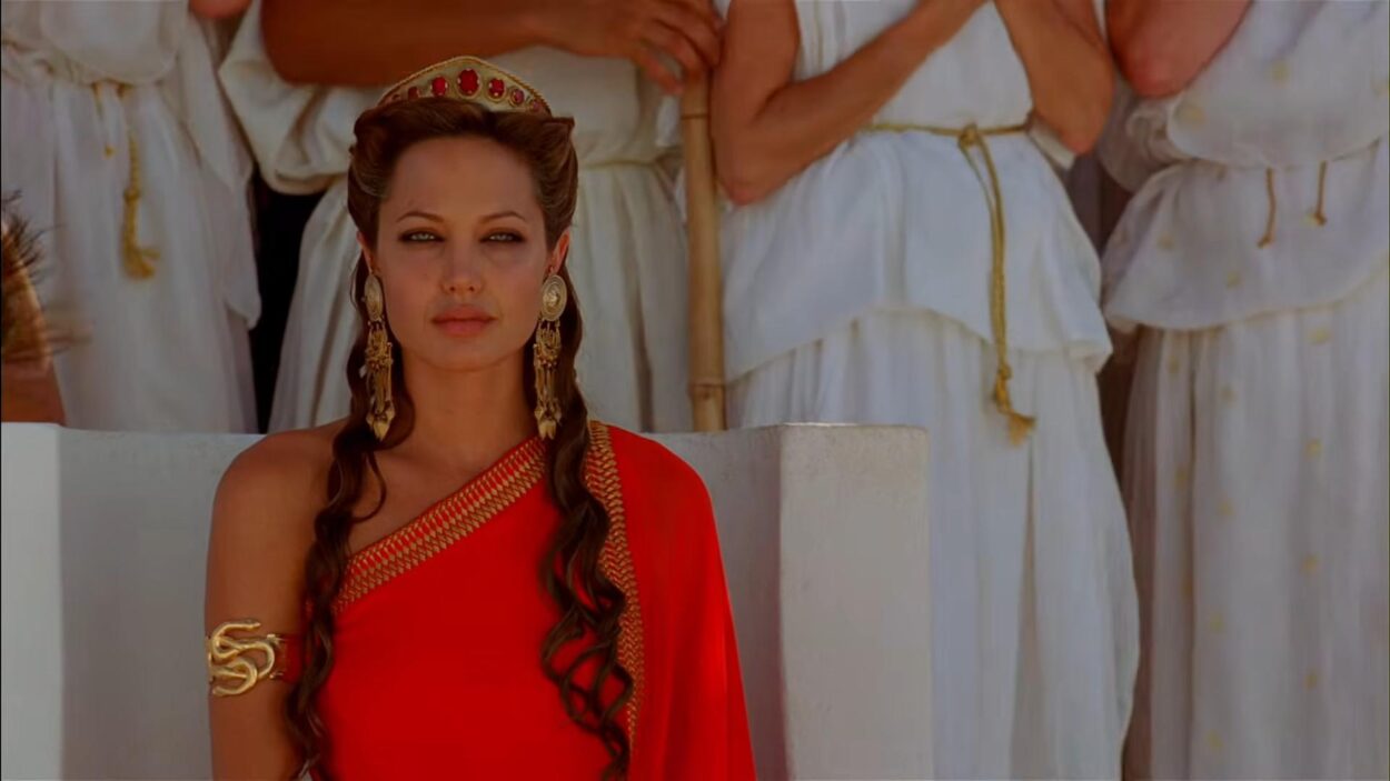 Woman wearing a red gown, gold jewelry and a jeweled crown