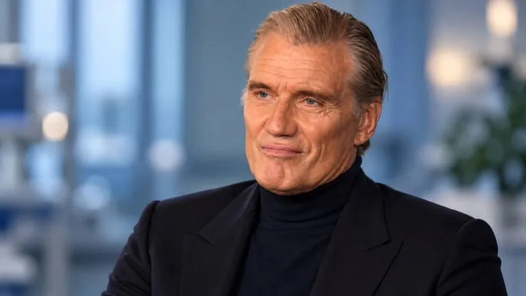 Dolph Lundgren in a black suit in a studio interview.