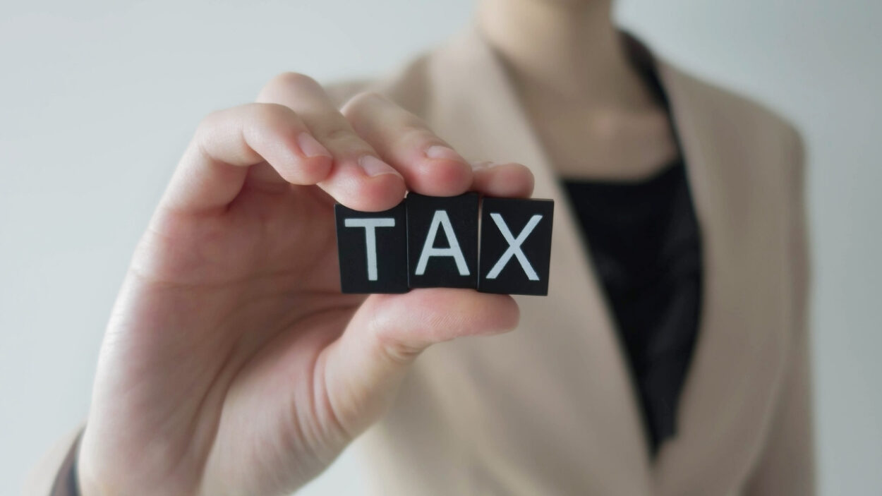 Businesswoman holds letter blocks that spell “TAX”