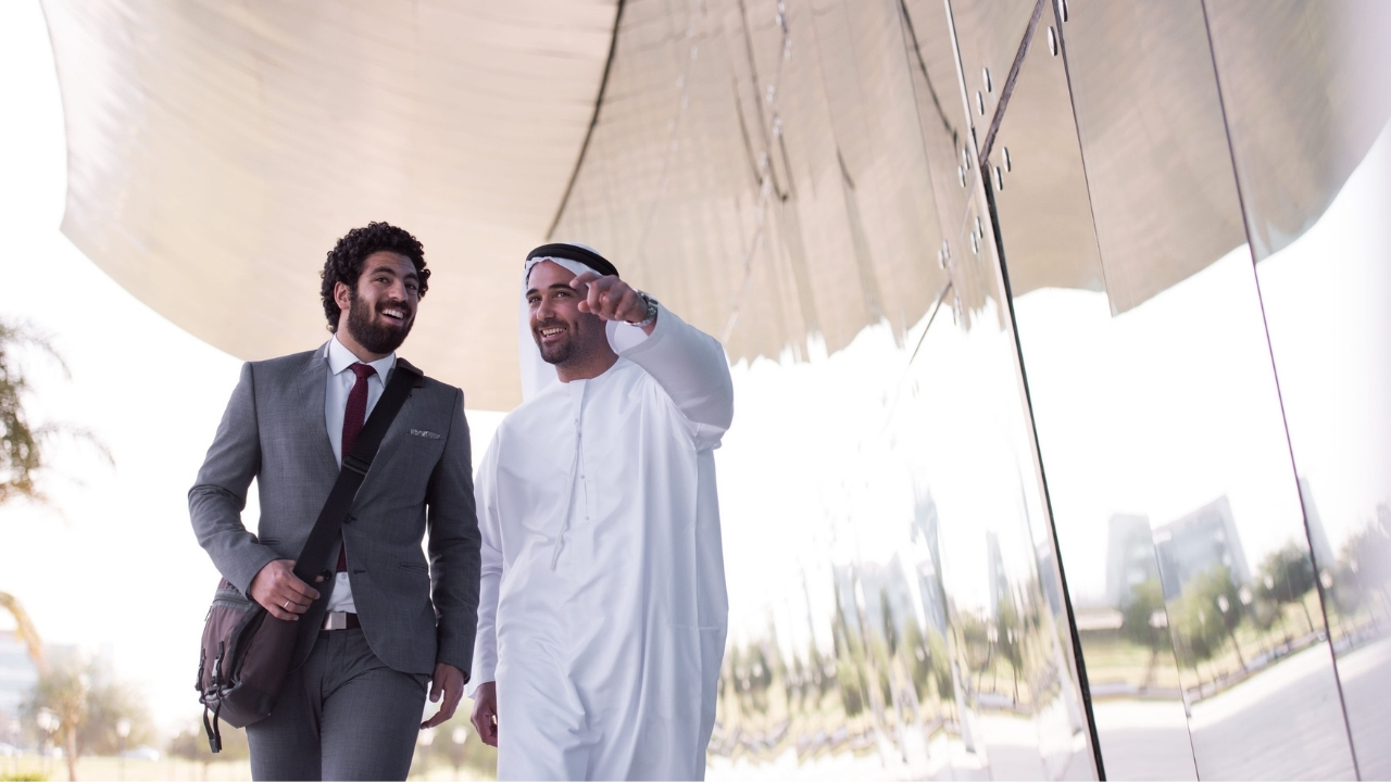Two businessmen walk outside a modern office complex in the UAE