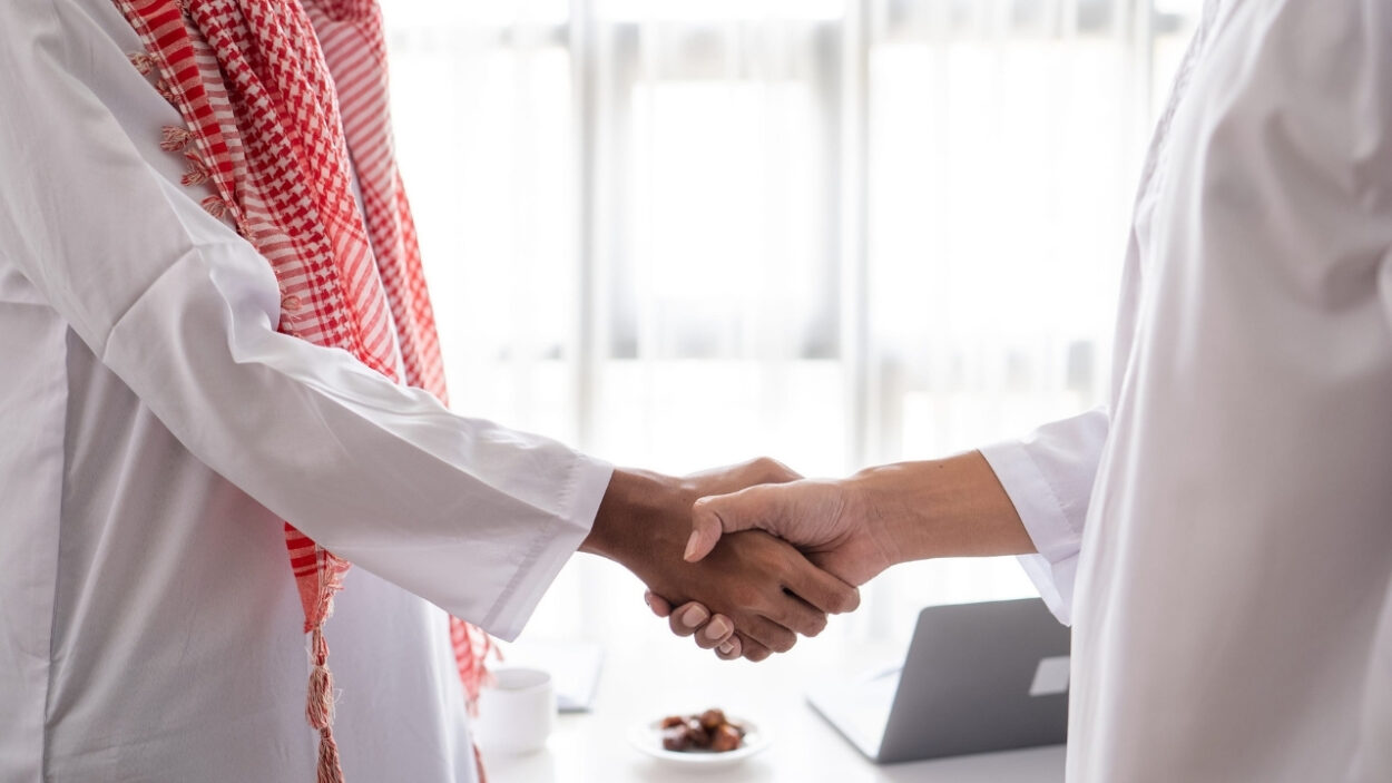 Two businesspeople shake hands in a UAE office