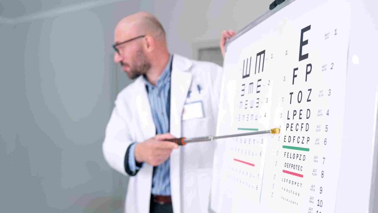 Healthcare professional pointing to an eye chart during a vision examination.